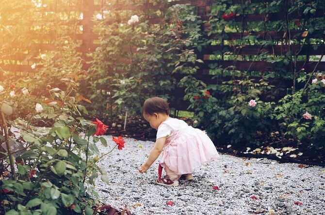 Kind loopt door een tuin met grind en een tuinafscheiding