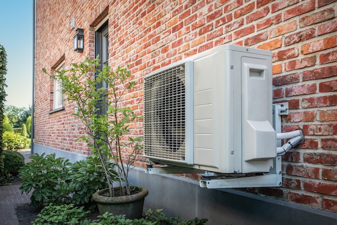 Warmtepomp bevestigd aan de buitenmuur van een woning.