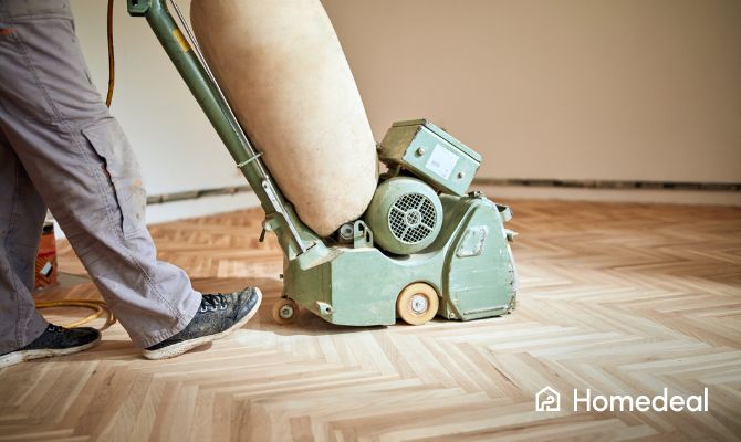 Vakspecialist die een houten vloer aan het schuren is